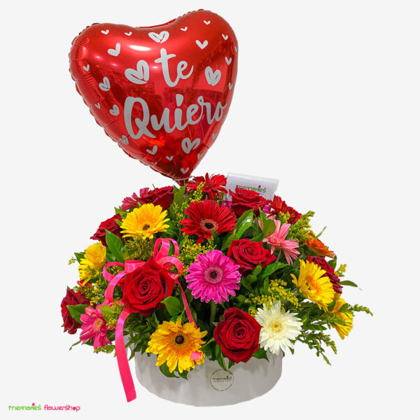 Arreglo floral visto desde la izquierda con gerberas multicolor, rosas rojas ecuatorianas, solidago y globo decorativo